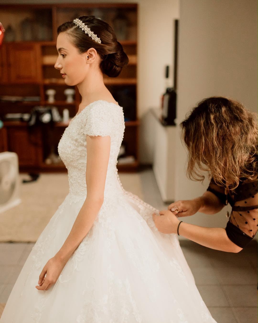 Auridiana ajustando o vestido de renda da noiva